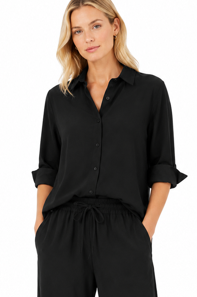 Close-up of a black boyfriend shirt featuring a classic collar, button-front closure and rolled cuffs in lightweight technical fabric