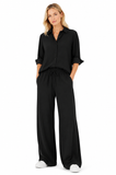 Model wearing a black oversized boyfriend shirt styled with matching wide leg pants and white sneakers, showcasing the relaxed fit and effortless drape.