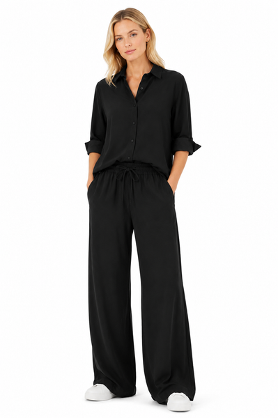 Model wearing a black oversized boyfriend shirt styled with matching wide leg pants and white sneakers, showcasing the relaxed fit and effortless drape.